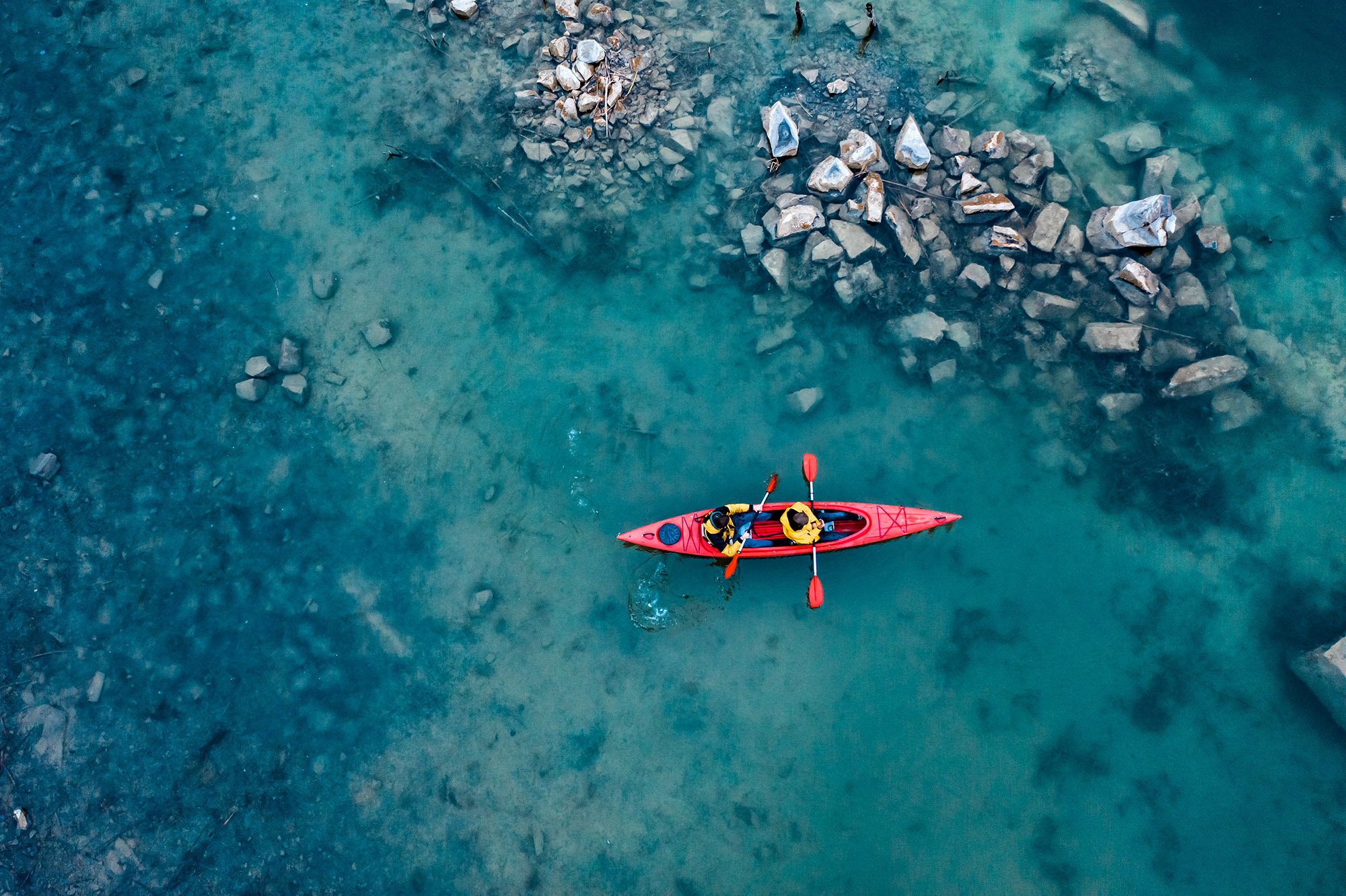 two athletic man floats on a red boat in river